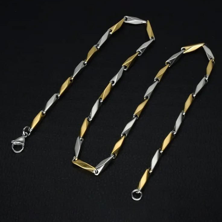 A two-tone chain necklace featuring alternating polished gold and silver-toned elongated links, displayed on a dark black background.