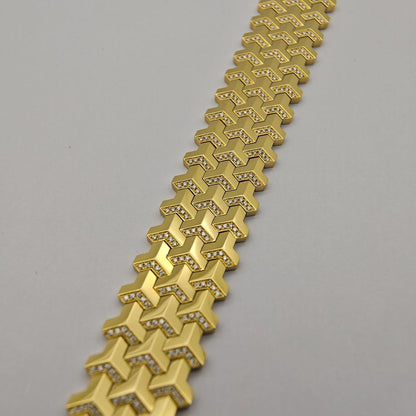 Gold bracelet with a geometric pattern on a gray background