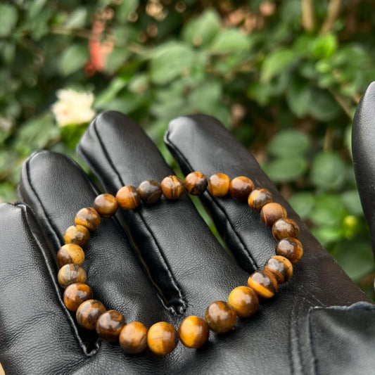 Brown beaded bracelet on a black gloved hand with a blurred green background