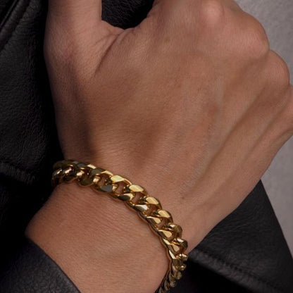 Hand wearing a gold chain bracelet on a dark background