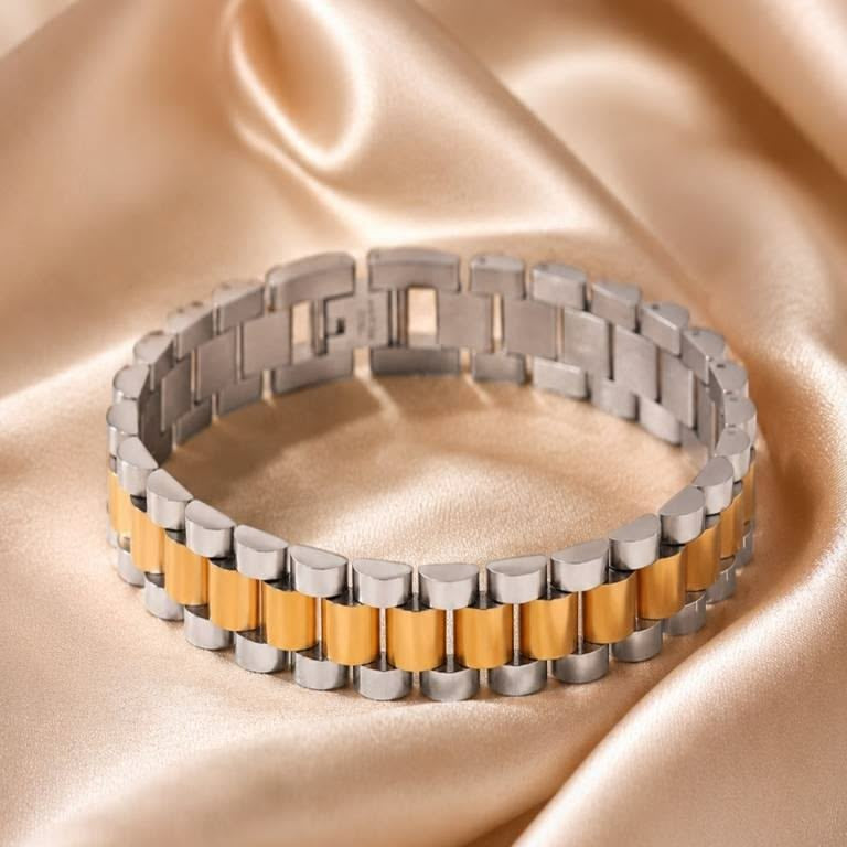 A two-tone metal link bracelet with silver and gold cylindrical links, displayed on a draped champagne satin fabric background.