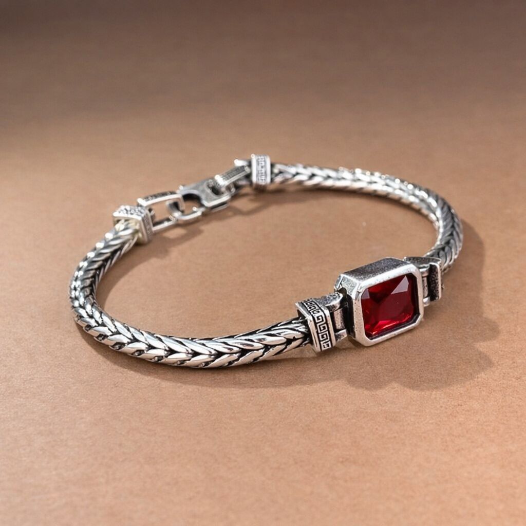 Silver bracelet with a red gemstone on a brown background