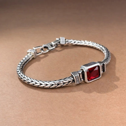 Silver bracelet with a red gemstone on a brown background