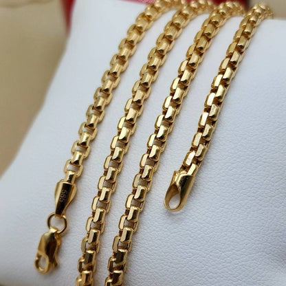 Three gold-tone chain necklaces of varying widths draped over a white display stand.