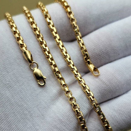 A gold-colored chain necklace with a lobster clasp, draped over a white textured fabric glove.