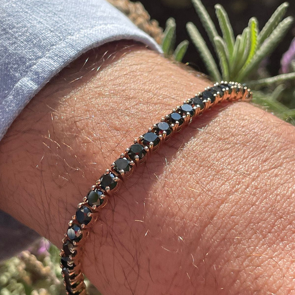 Rose gold bracelet with black stones on a wrist against a natural background