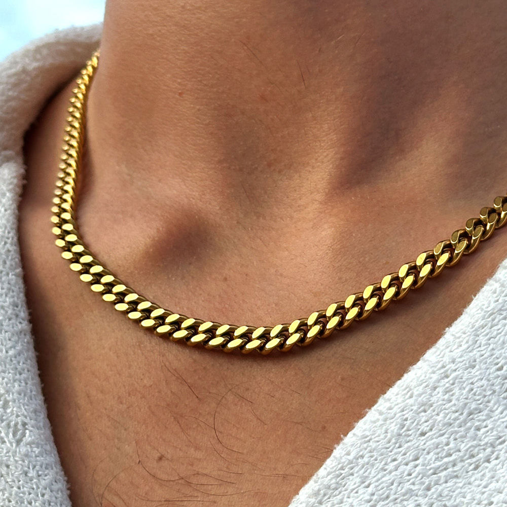 Gold chain necklace worn by a person with a white garment partially visible