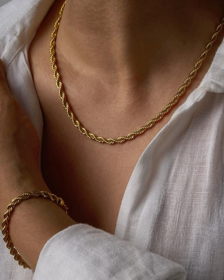 Gold necklace and bracelet on a person wearing a white shirt