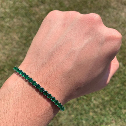 Hand wearing a green beaded bracelet against a grassy background