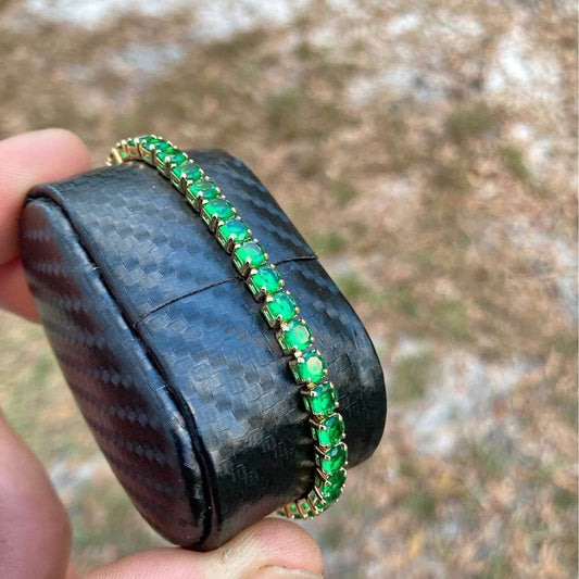 Black case with green gemstones held by a hand against a blurred natural background