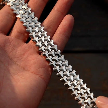 Silver bracelet held in a hand with a blurred background