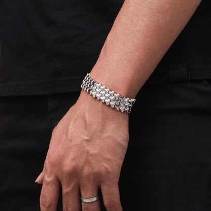 Hand wearing a silver bracelet on a black background