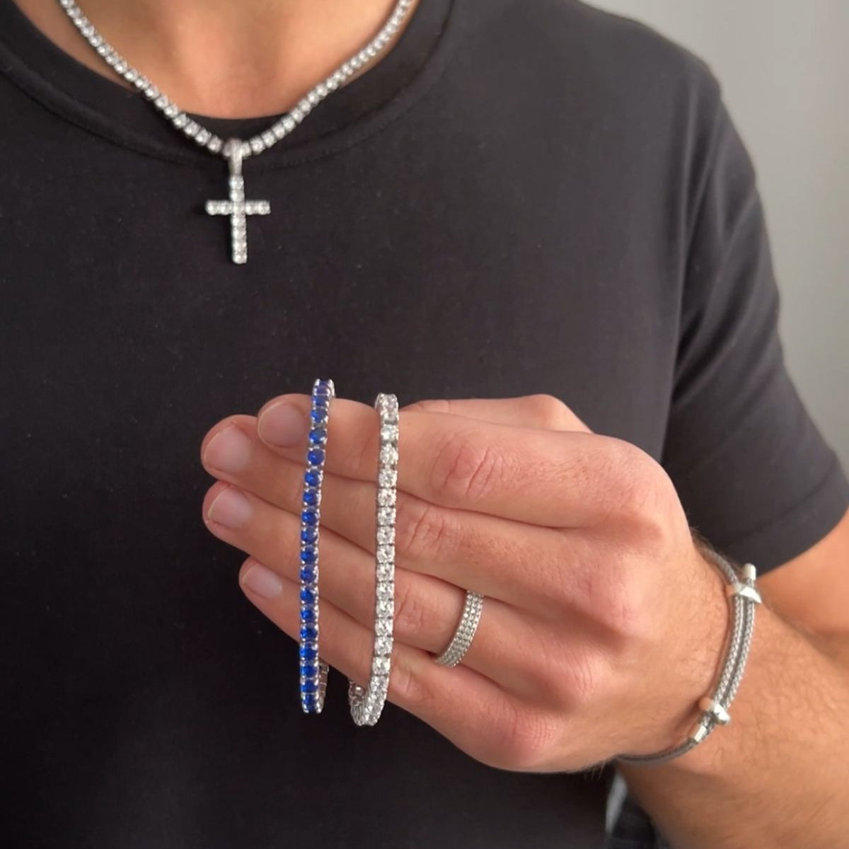 Person wearing a necklace, bracelet, and ring with a plain background