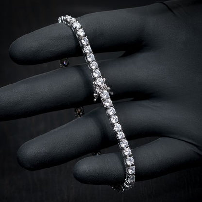 Silver bracelet with clear stones held by a gloved hand against a dark background