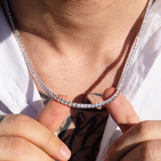 Person wearing a silver chain necklace with a blurred background