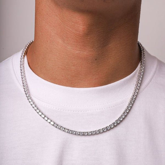 Silver chain necklace worn by a person on a plain background