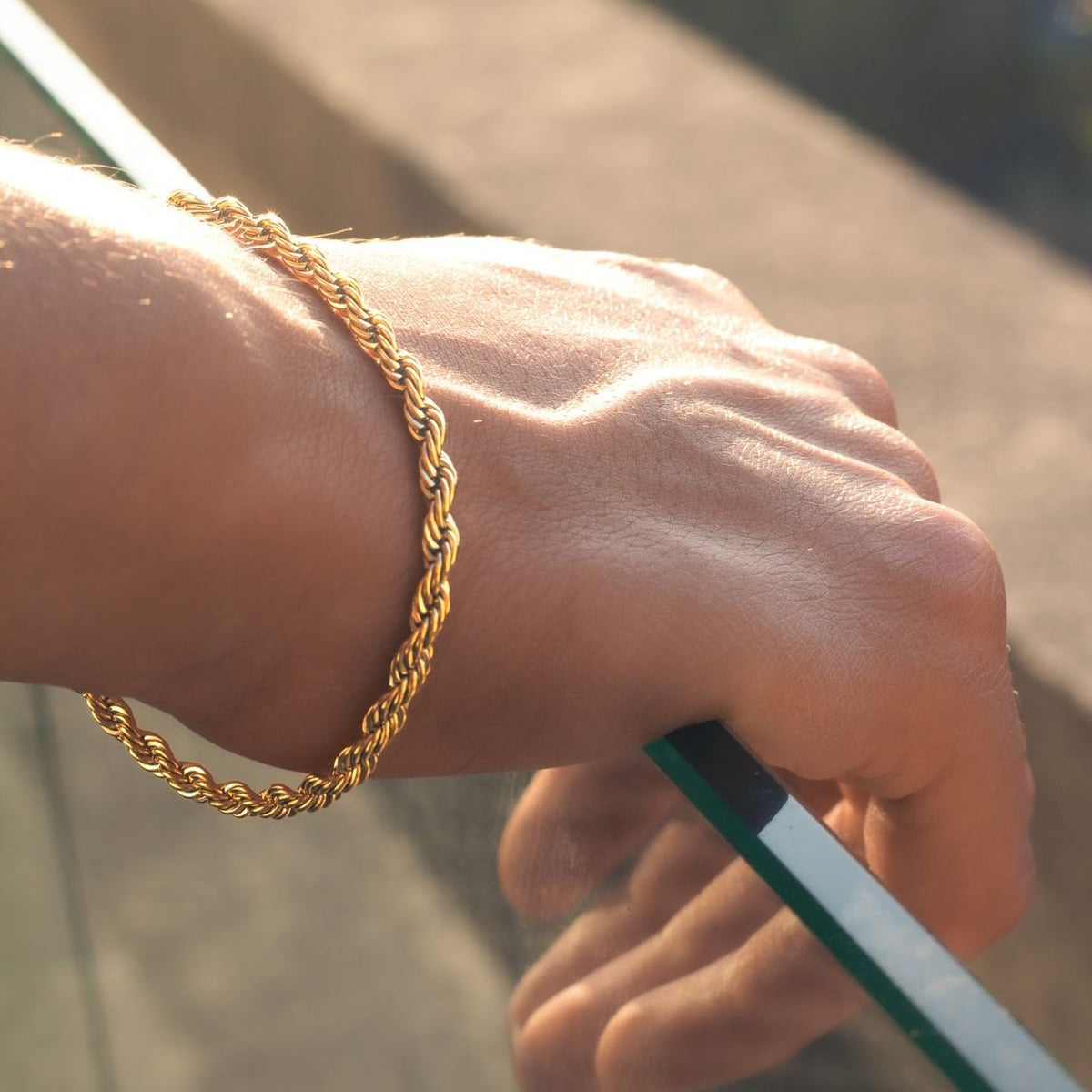 Hand wearing a gold bracelet with a blurred background