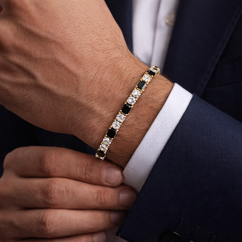 Close-up of a person wearing a gold bracelet with black and white stones on a suit sleeve.