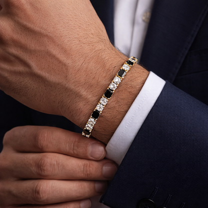 Close-up of a person wearing a gold bracelet with black and white stones on a suit sleeve.