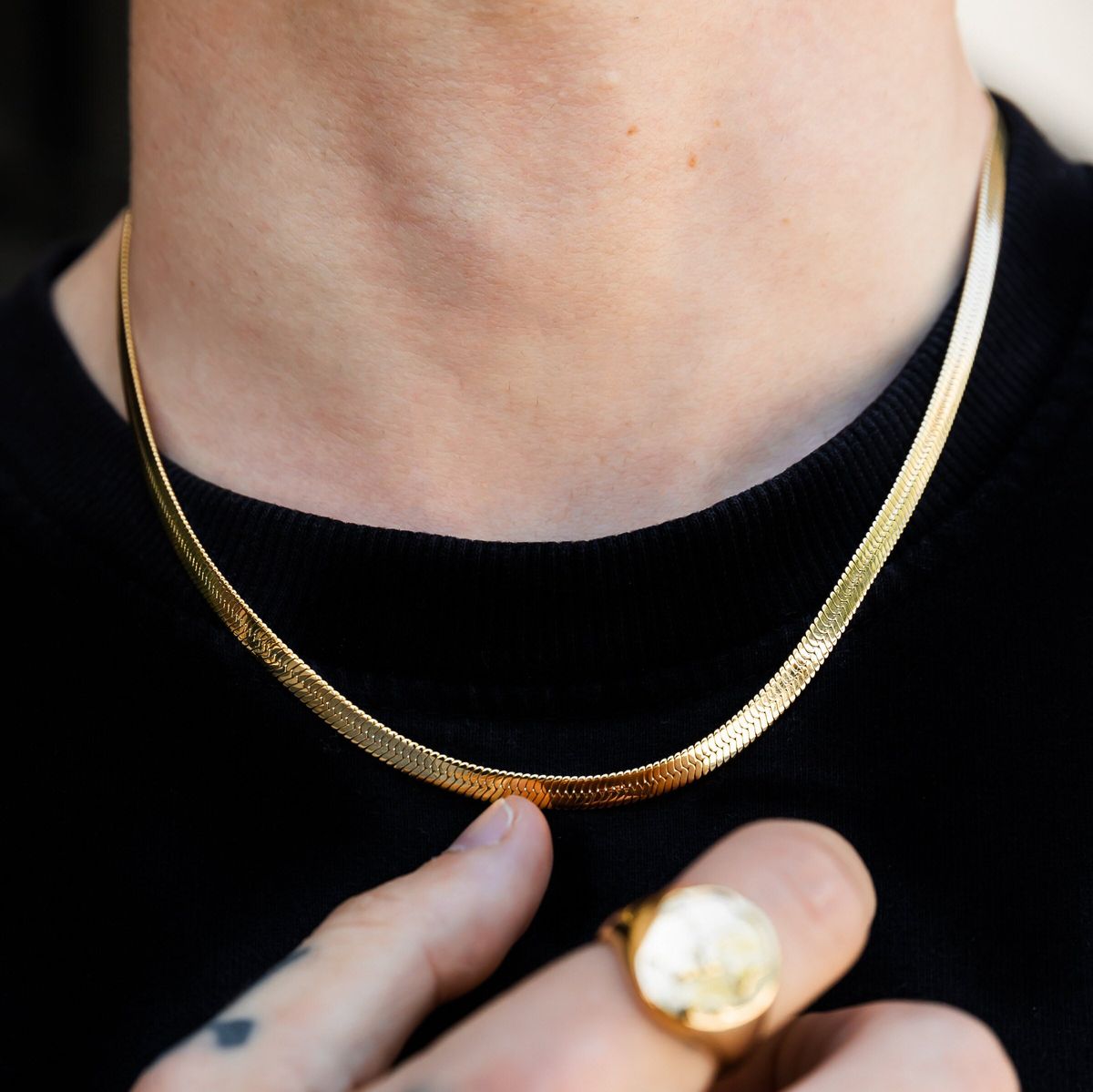 Gold necklace being worn with a black background