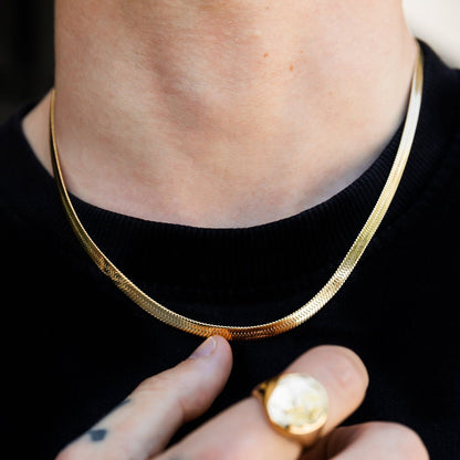 Gold necklace being worn with a black background