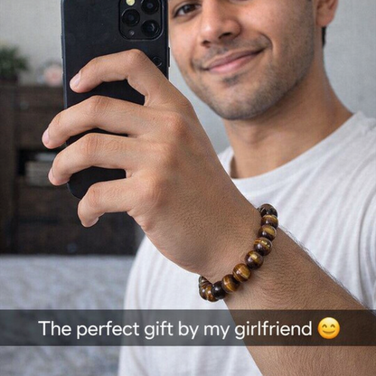 Man holding a phone with a bracelet on his wrist, smiling.